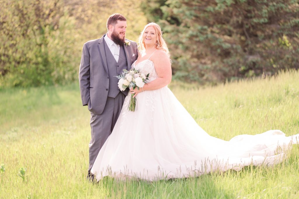 aiden laurette photography | red headed woman and bearded man in wedding attire standing in a green field on a sunny day
