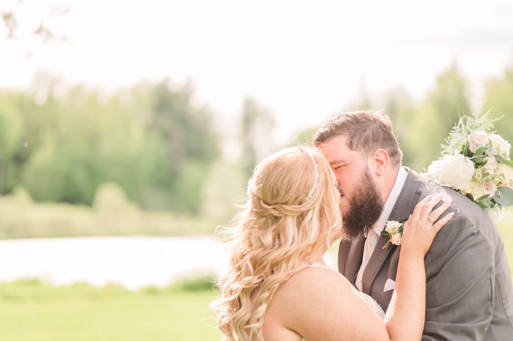 aiden laurette photography | bride and groom kiss on grass in front of trees