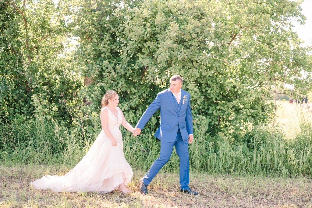 Aiden Laurette Photography | bride and groom walk in front of trees