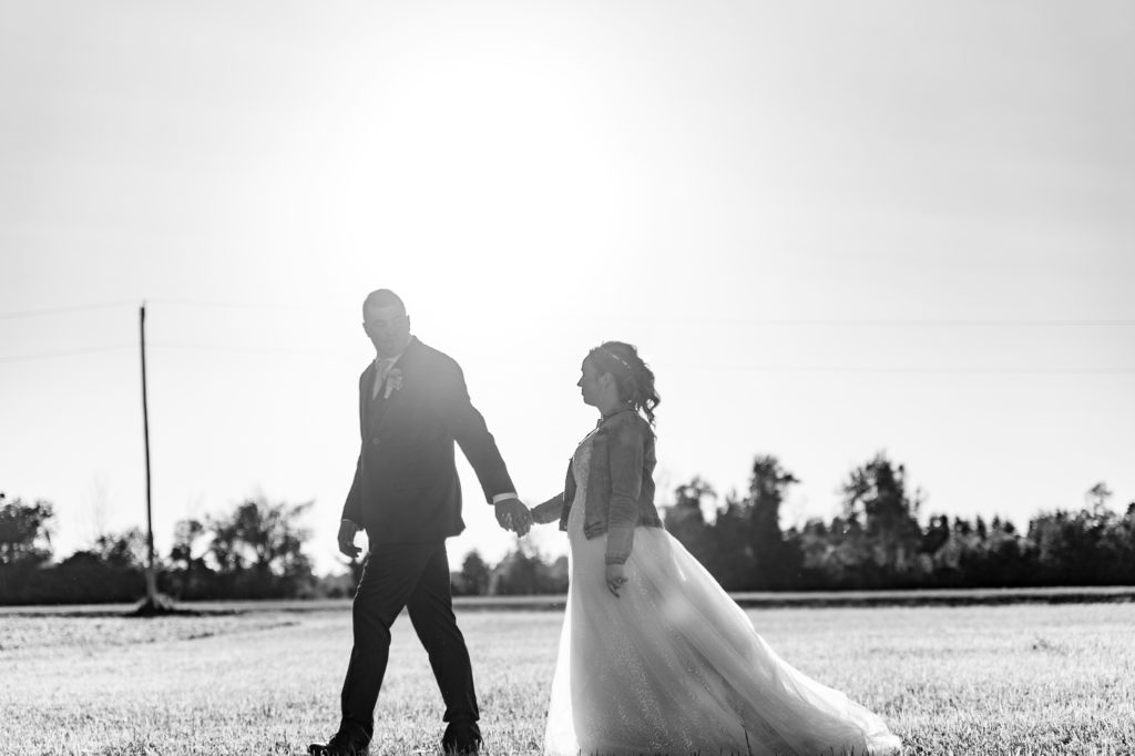 Aiden Laurette Photography | black and white photo of bride and groom walking in field