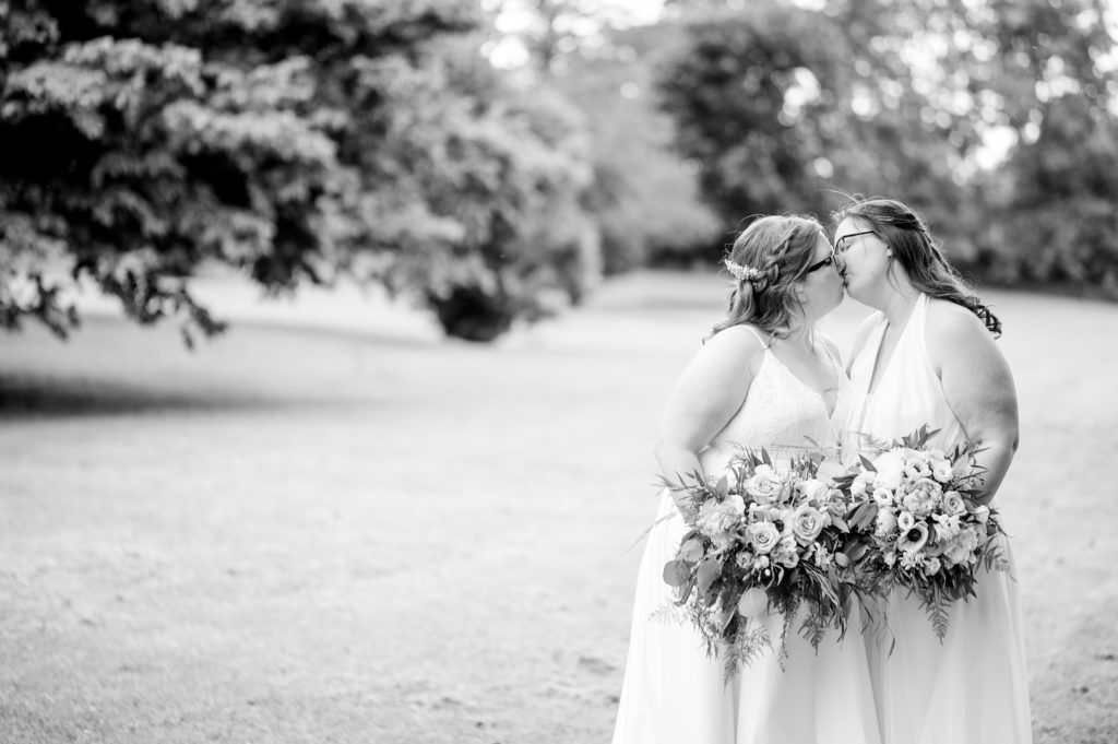 Aiden Laurette Photography | black and white photo of brides kissing in field
