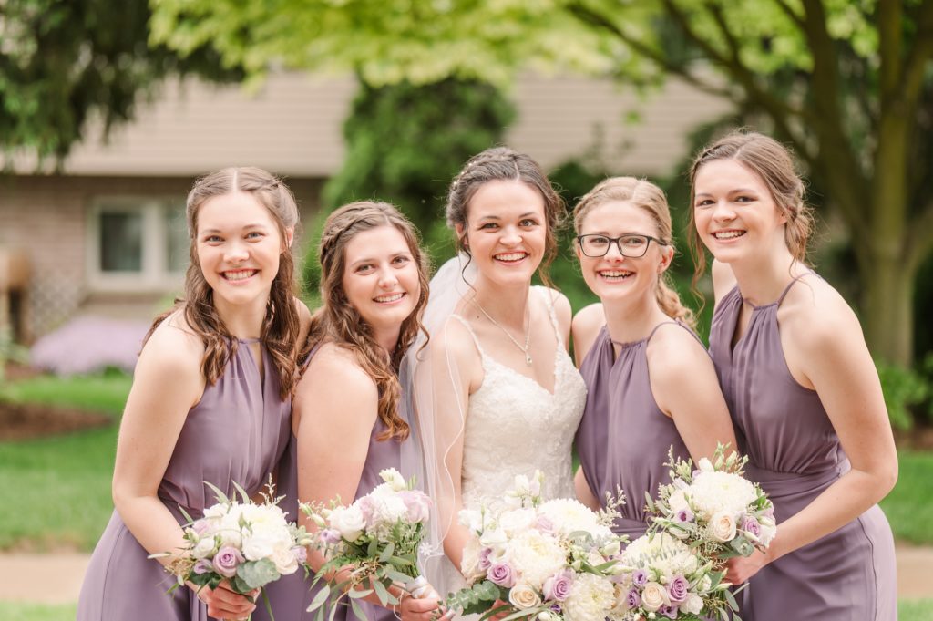 Aiden Laurette Photography | bride poses with four women in purple formal dresses holding flowers