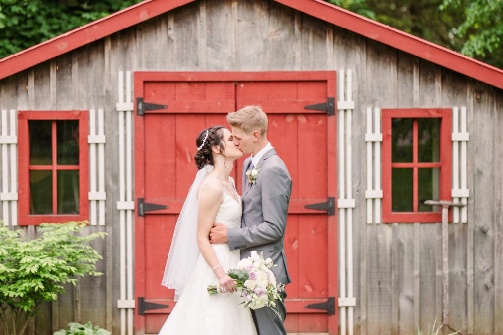 Aiden Laurette Photography | bride and groom kiss in front of barn with red doors and windows
