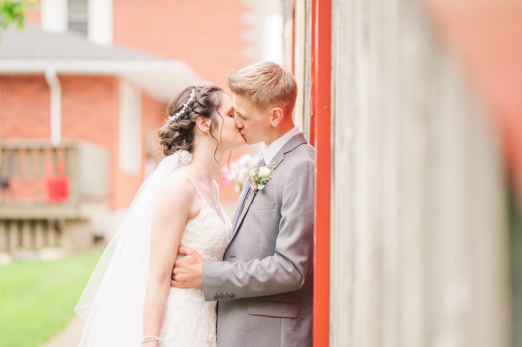 Aiden Laurette Photography | bride and groom kissing against side of barn