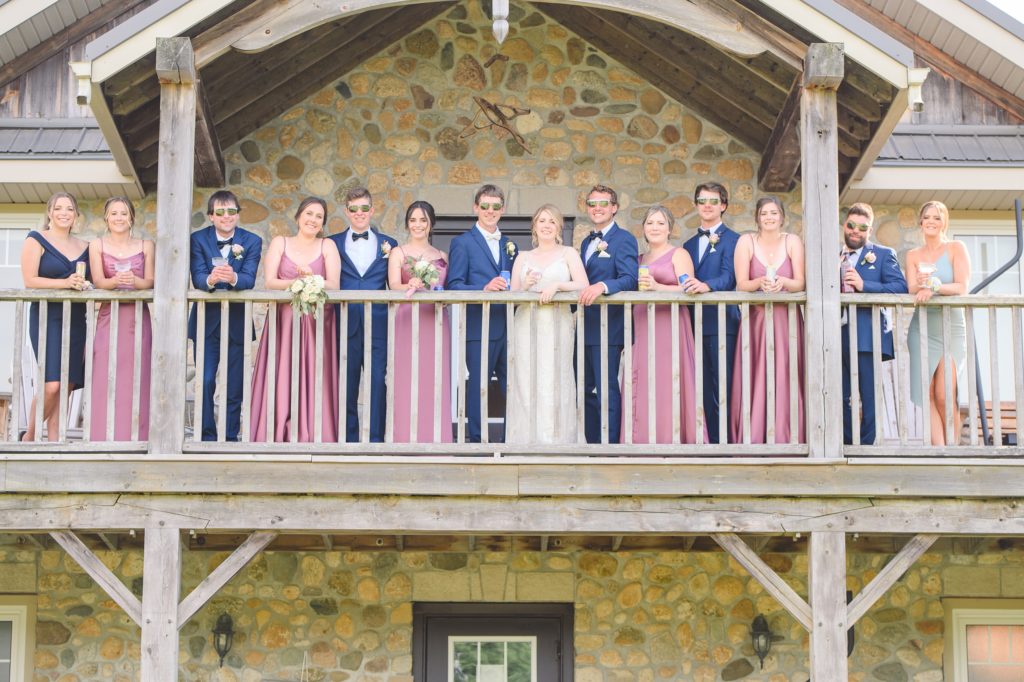 Aiden Laurette Photography | bride and groom stand on balcony flanked by wedding party