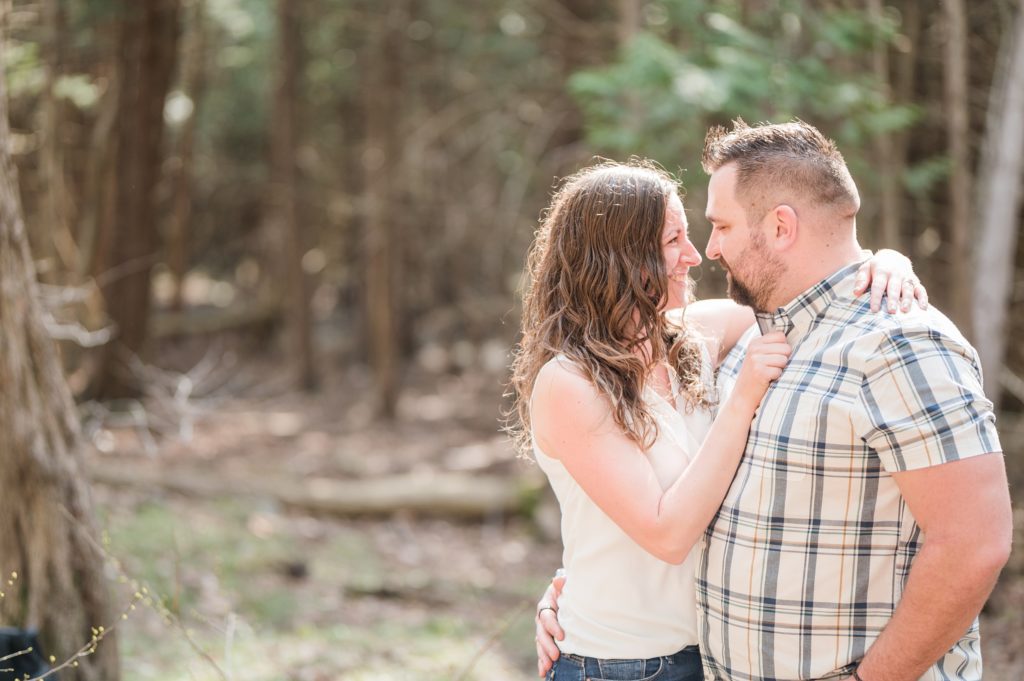Aiden Laurette Photography | Preparing for an Engagement Session | A brunette man and woman embrace smiling in the woods