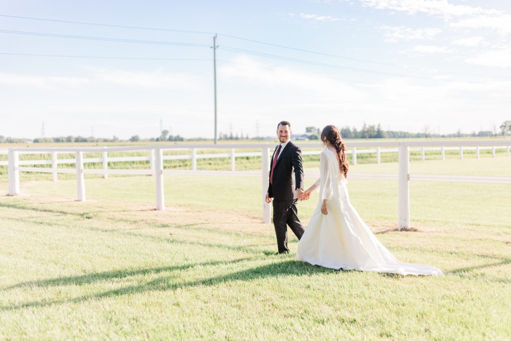 Aiden Laurette Photography | man and woman walk on grass holding hands with field in background