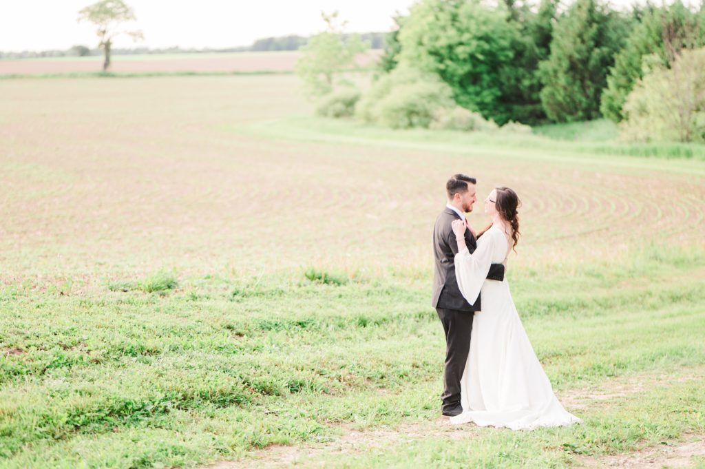 Aiden Laurette Photography | bride and groom stand in field