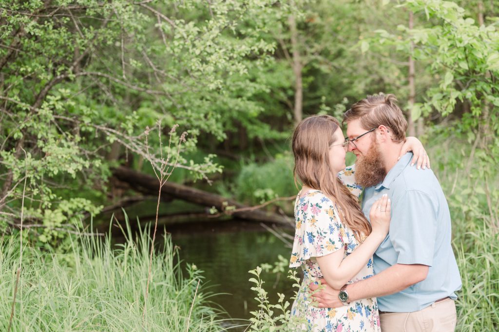 Aiden Laurette Photography | man and woman almost kissing standing in front of greenery and creek
