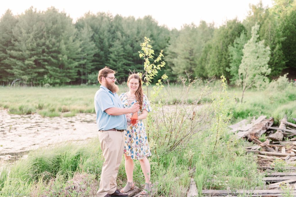 Aiden Laurette Photography | man and woman open bottle of wine surrounded by greenery