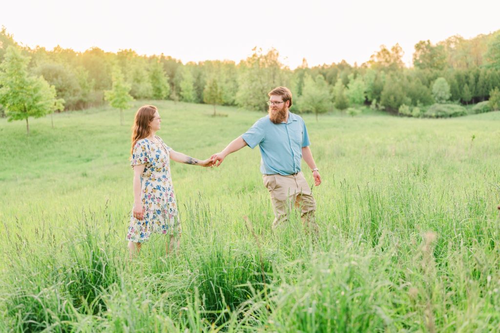 Aiden Laurette Photography | man and woman standing in field holding hands and walking
