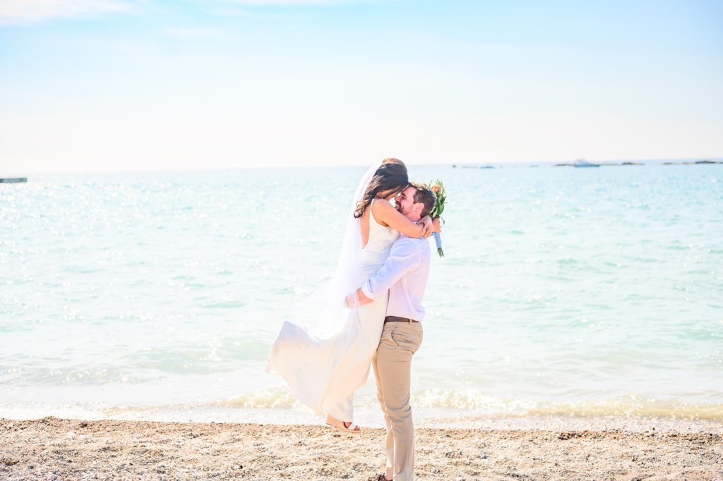 Aiden Laurette Photography | bride and groom stand on beach in front of water