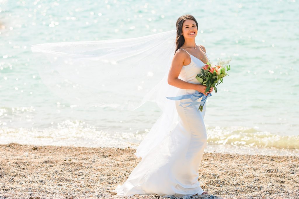 Aiden Laurette Photography | bride stands on beach in front of water