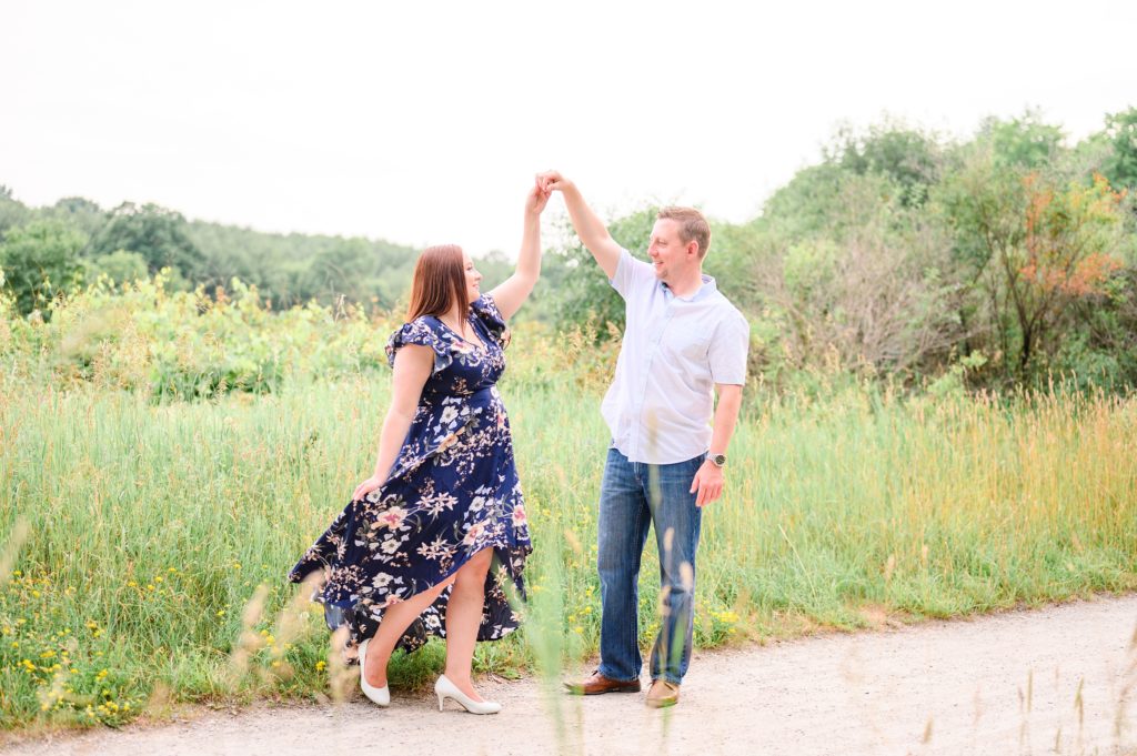 Aiden Laurette Photography | man and woman twirl in front of green field