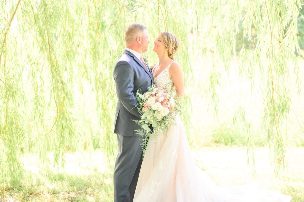 Aiden Laurette Photography | bride and groom pose in field under willow tree