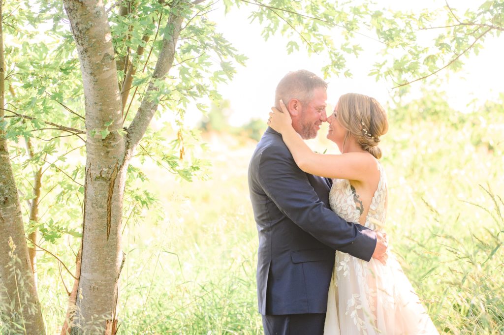Aiden Laurette Photography | bride and groom kiss in front of willow trees in field