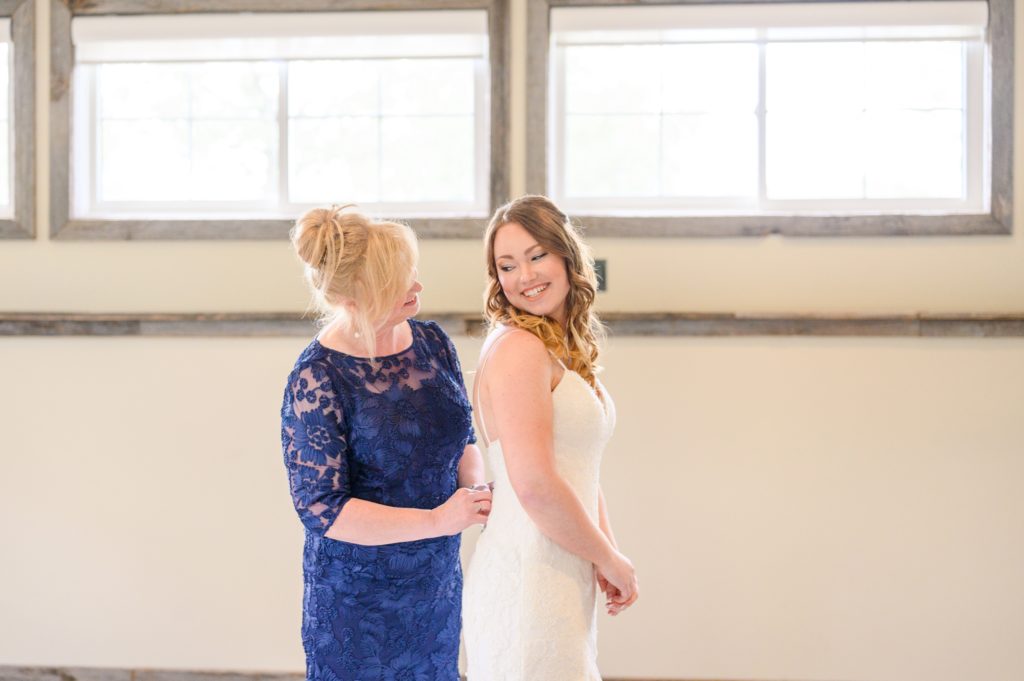 Aiden Laurette Photography | blonde woman in blue dress zips up brides gown