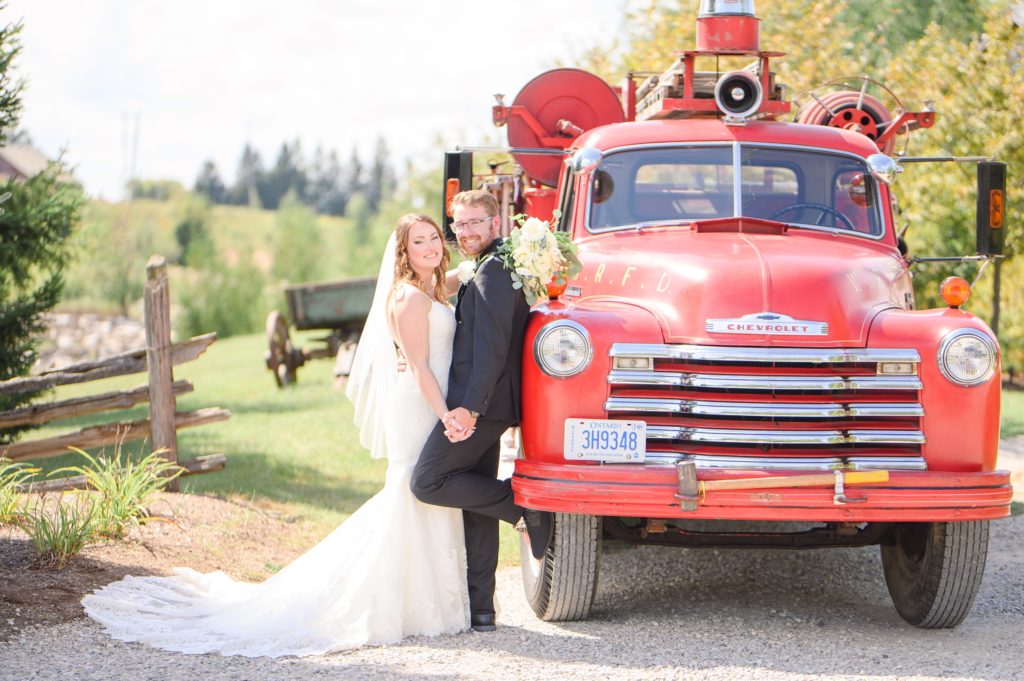 Aiden Laurette Photography | bride and groom pose with antique firetruck