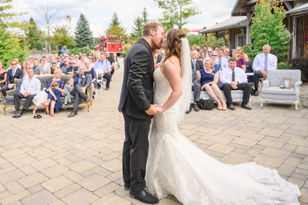 Aiden Laurette Photography | bride and grooms first kiss as wedding guests look on