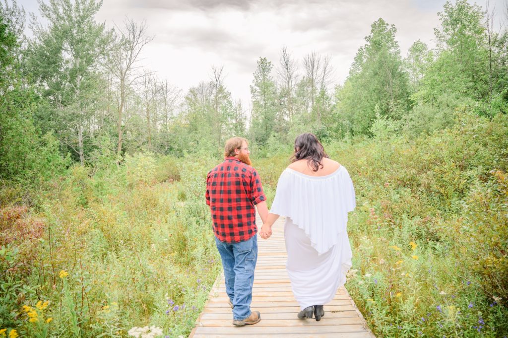 Aiden Laurette Photography | Woman in white dress and man in plaid shirt walk down field path