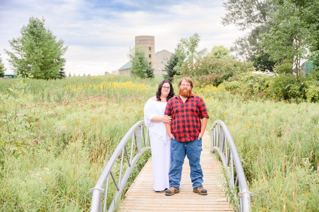 Aiden Laurette Photography | Woman in white dress and man in plaid shirt stand on bridge