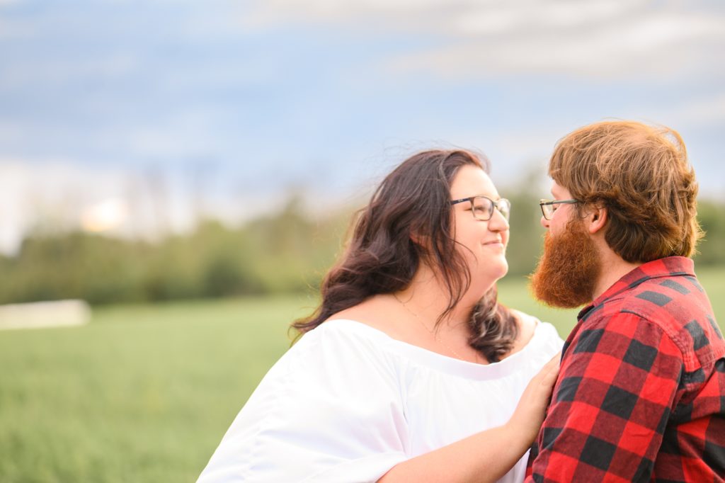 Aiden Laurette Photography | Woman in white dress and man in plaid shirt embrace in field
