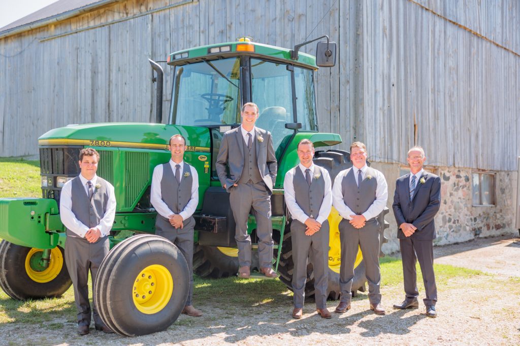 Aiden Laurette Photography | groom poses with groomsmen in front of tractor