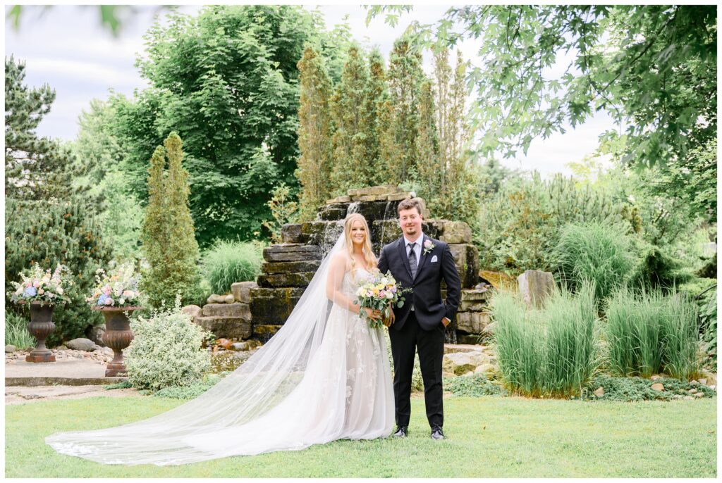 Aiden Laurette Photography | bride and groom pose in front of greenery